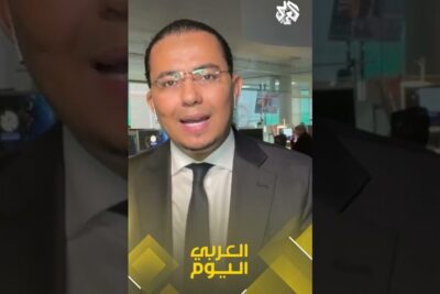 Male news presenter in a suit speaking on-camera in a newsroom with Arabic on-screen graphics, imod okkupanter