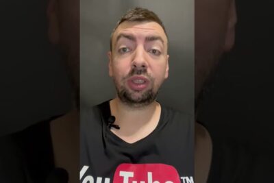 Close-up of a man speaking to camera with a lapel mic wearing a YouTube shirt about imod ytringsfrihed.