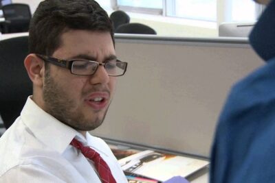 A frustrated office worker with glasses reacting at his desk in capitalist office environment