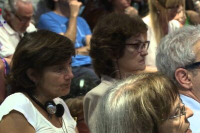 Audience members wearing headsets listening intently to a talk on inmigracion impacto.