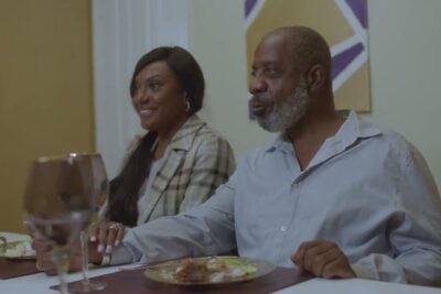 Mature couple smiling and holding hands at a dining table during a cozy meal, intended parents 2.