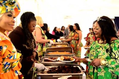 Women in colorful attire serving and receiving food at an internationale femmes buffet