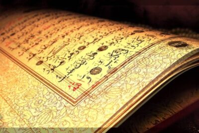 Open ornate Arabic illuminated manuscript showing gold calligraphy and floral margin decorations, jeesuksen marian.