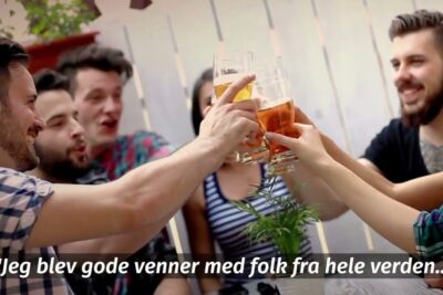 Group of young people toasting with beers outdoors, celebrating new connections for job udlandet.