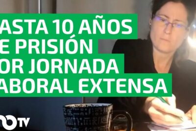 Person working late at a desk under a lamp emphasizing jornada laboral legal warning