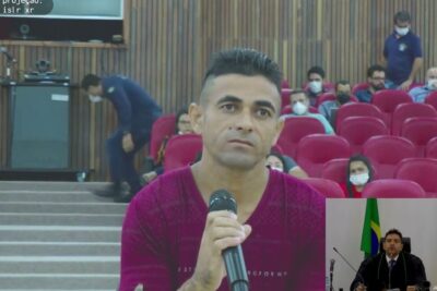 Man holding a microphone in a courtroom during julgamento juri 1
