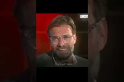 Smiling bearded man wearing glasses in a red-lit interview setting, juryen vare.