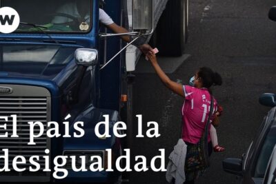 Masked woman hands money to a truck driver through a truck window in congested traffic, reflecting justicia social 1.