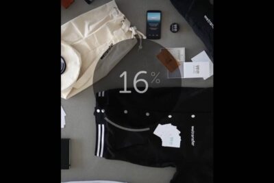 Flat-lay of branded tech and apparel including a smartphone, canvas tote, and black jacket with a translucent 16% progress overlay, kahootin kaytto 2