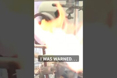 Laboratory apparatus producing a large flame and sparks during a kemisk syntes 3 experiment with on-screen text I WAS WARNED.