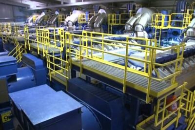 Large industrial generator hall with yellow safety railings and metal catwalks highlighting kestavaa kehitysta