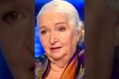 Senior woman with white hair in a neat bun wearing a colorful silk scarf during a studio interview, kognitiva formagor.