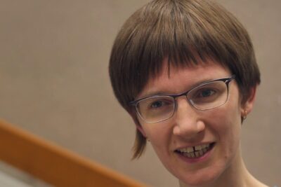 Close-up portrait of a person wearing glasses and speaking, related to konventionelle medizin 1.
