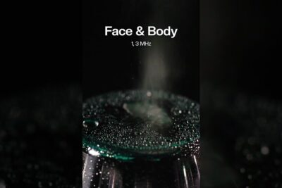 Close-up of a wet Face & Body treatment applicator with droplets and mist suggesting kosmetiske operasjoner