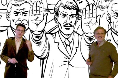 Two men stand before a high-contrast black-and-white illustration of suited figures raising open hands, evoking kun rehellisia.