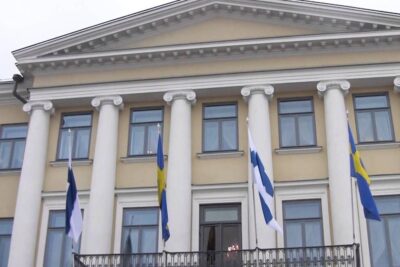 Neoclassical building facade with tall white columns, balcony and Finnish and Swedish flags, kuningas kuningatar 1.
