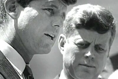 Black-and-white close-up of two men in suits in conversation, kuuban hallintoa 1.