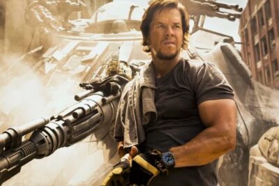 A rugged action hero beside a massive gatling gun and damaged aircraft in a dusty urban battlefield for la caza 2.