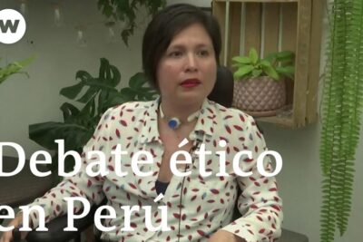 Woman seated in an interview setting with a visible medical airway device and plants in the background, la eutanasia 14