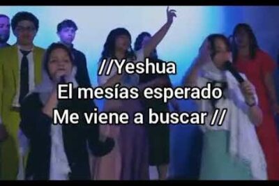 Choir and worship leaders singing on stage with projected Spanish lyrics at la iglesia 1.