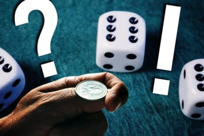 A hand flipping a coin amid dice on green felt evoking le hasard and random outcomes.