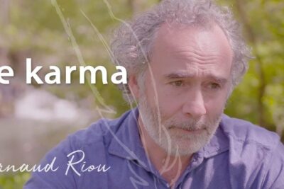 Contemplative bearded man outdoors with 'le karma' text overlay.