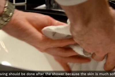 Person's hands drying with a towel at a bathroom sink after le rasage.