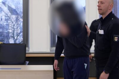 Defendant escorted by a court officer inside a courtroom before a lebenslangen haftstrafe 1 proceeding.