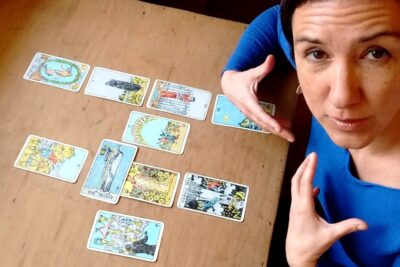 Woman in blue top presenting a spread of tarot cards on a wooden table during lecturas tarot