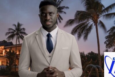 Man in beige suit and navy tie standing by palm trees and pool at dusk for leducation physique 1