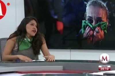 Female news presenter wearing a green scarf next to a screen showing a person holding a green cloth, legalizacion aborto 11