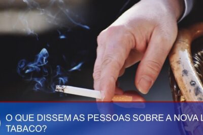 Hand holding a lit cigarette with rising smoke and a visible banner mentioning lei tabaco