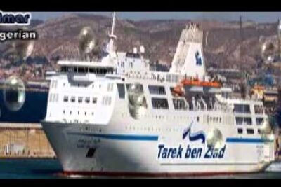 White passenger ferry docked at a sunny harbor with coastal hills and lifeboats, evoking les vacances