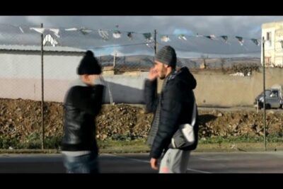 Two blurred figures on an outdoor court evoking les zombies in motion.