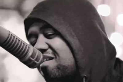 Black-and-white close-up of a hooded singer performing into a microphone, captured for livre arbitrio 1.