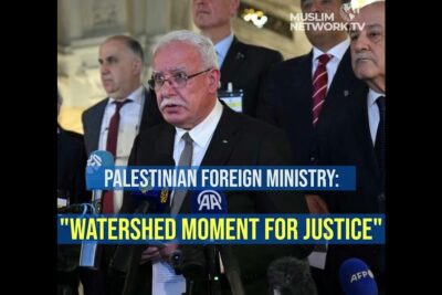 A Palestinian official addresses reporters at a podium about loccupation illegale amid microphones and press banners