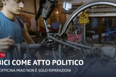 Young mechanic repairing an inverted bicycle frame and wheel in a cluttered indoor workshop, luso bicicletta.