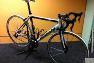Sleek luso biciclette road bike with drop handlebars and thin tires leaning on a stand indoors.