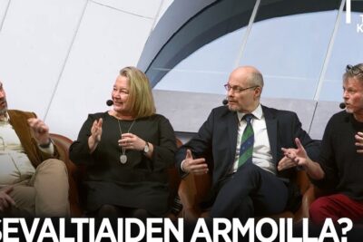 Four panelists seated with microphones in a conference setting discussing global economic order, maailmantalouden jarjestyksen 1.