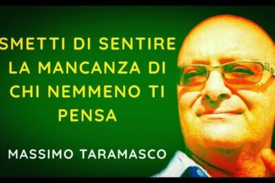 Close-up portrait of a man in glasses beside bold green and yellow text about mancanza