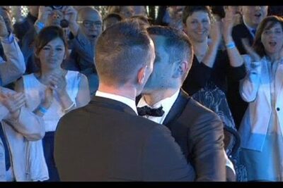 Two grooms share a kiss at matrimonio omosessuale 5 while guests applaud and smile
