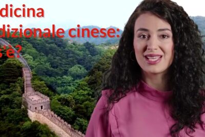 Female presenter in pink blouse with Great Wall backdrop discussing medicina convenzionale