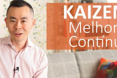 Man seated on a couch with an orange Kaizen banner displaying melhoria continua 1 and a colorful geometric cushion