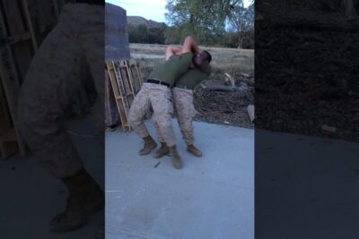 Two service members practicing a close-quarters takedown during military service 1 training outdoors.