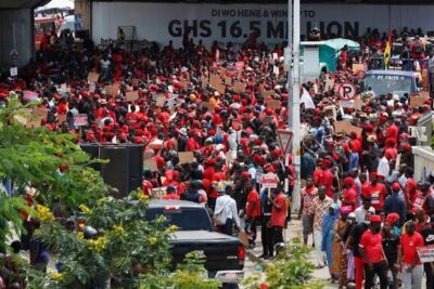 Crowd of red-shirted protesters carrying placards under an overpass for miniere illegale 1