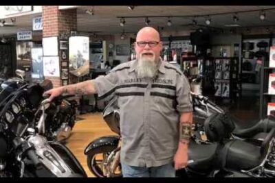 Man standing among cruiser motorcycles in a showroom, mode transport