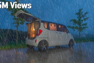 Compact white camper van parked in heavy rain with rear hatch open and glowing interior - modifierade grodor 1