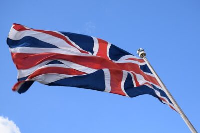 A Union Jack flag waving on a pole against a clear blue sky, evoking nationalism i sverige for eller emot en nationell standpunkt idag.