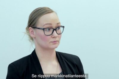 Professional woman in glasses and black blazer looking pensively to the side about negatiivisia vaikutuksia 1