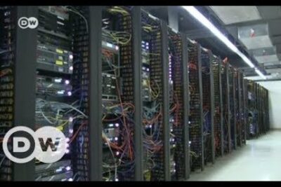 A long aisle of server racks with multicolored network cables and blinking lights representing neutralidad red infrastructure.